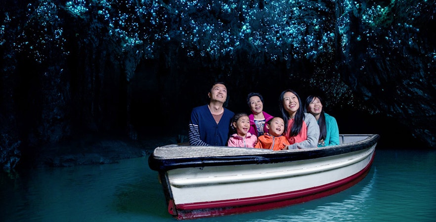 Group enjoying boat tour under glowworms in Waitomo Caves, New Zealand.