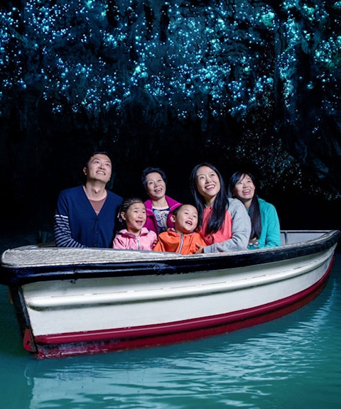 Group enjoying boat tour under glowworms in Waitomo Caves, New Zealand.