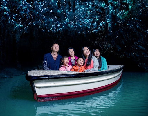 Group enjoying boat tour under glowworms in Waitomo Caves, New Zealand.