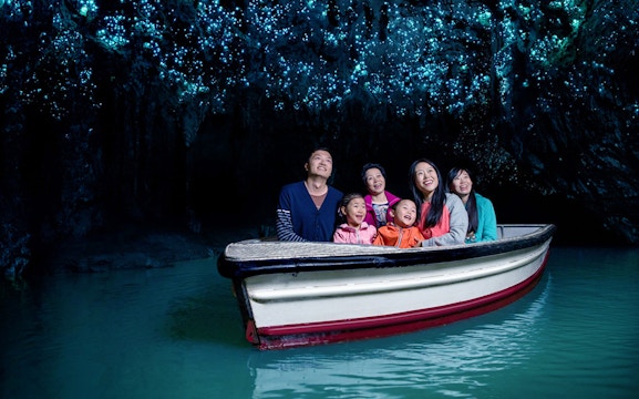 Group enjoying boat tour under glowworms in Waitomo Caves, New Zealand.