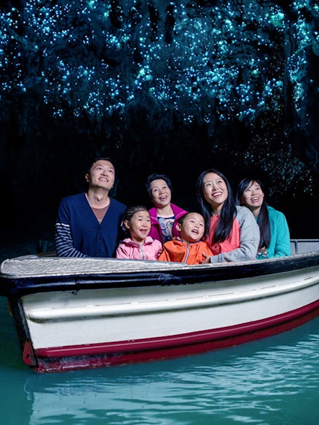 Group enjoying boat tour under glowworms in Waitomo Caves, New Zealand.