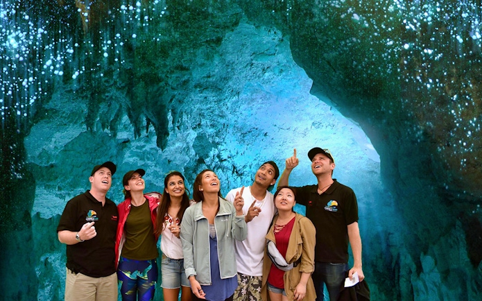 Group exploring glowworm-lit Waitomo Caves on Auckland tour.