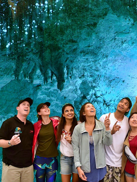 Group exploring glowworm-lit Waitomo Caves on Auckland tour.