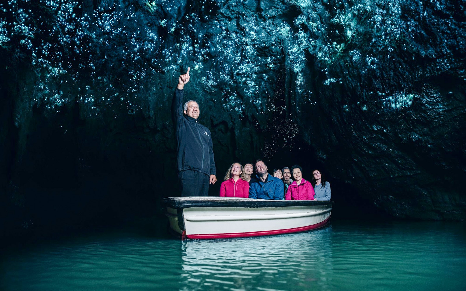 Tourists on a boat admire glowworms in Waitomo Caves, Auckland.