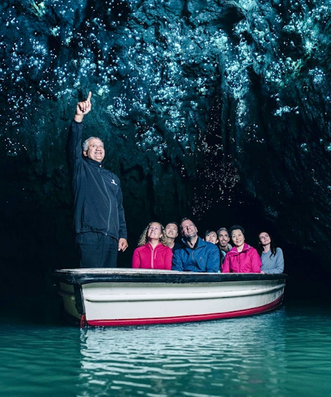 Tourists on a boat admire glowworms in Waitomo Caves, Auckland.