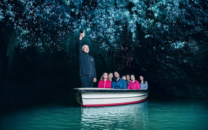 Tourists on a boat admire glowworms in Waitomo Caves, Auckland.