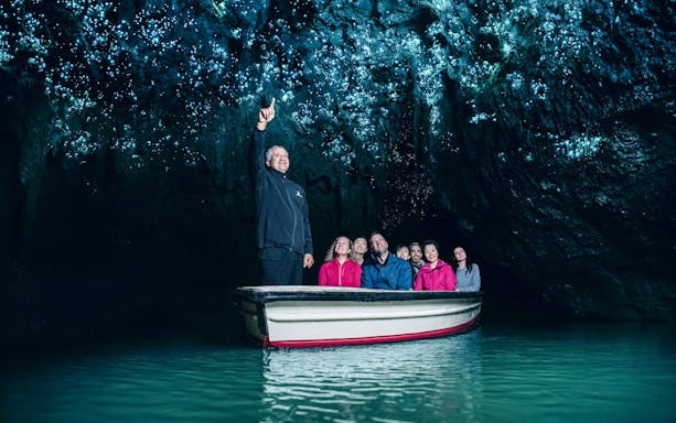 Tourists on a boat admire glowworms in Waitomo Caves, Auckland.