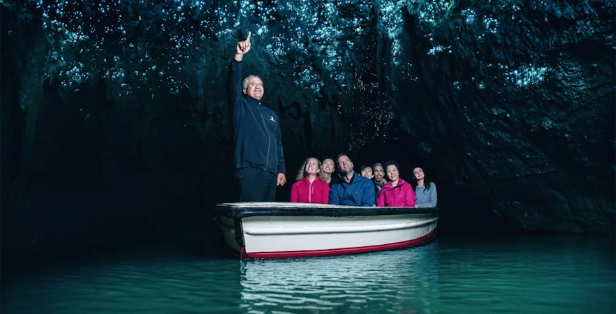 Guided river boat ride through illuminated Waitomo Caves, New Zealand.