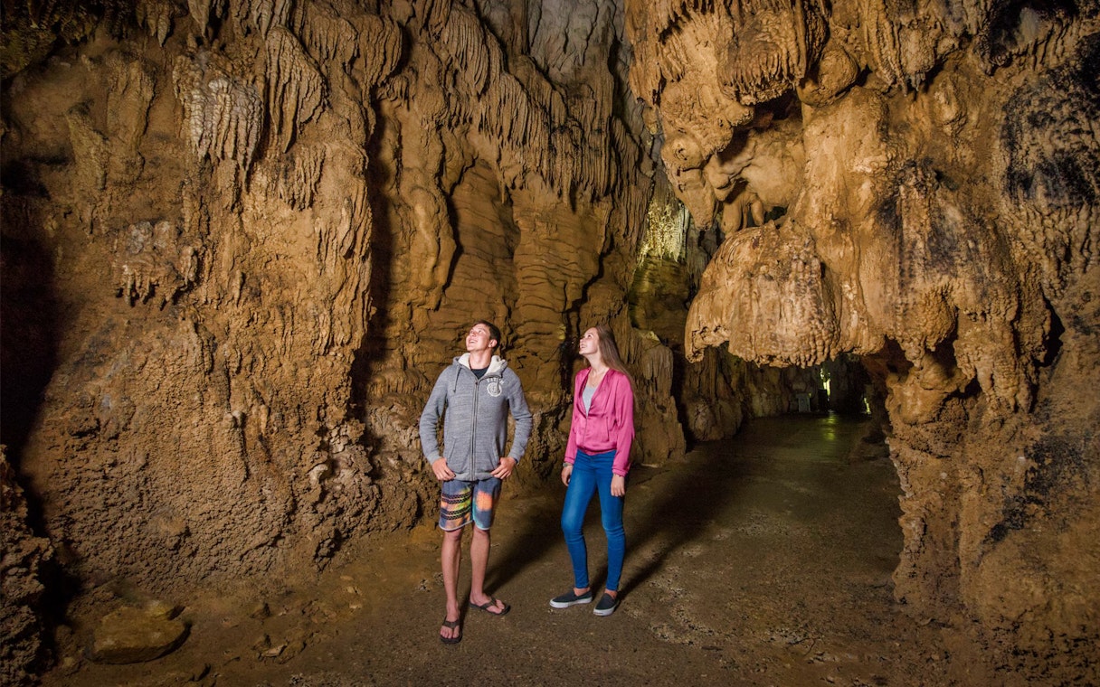 Tourists exploring stalactites in Waitomo Caves, Auckland, New Zealand.