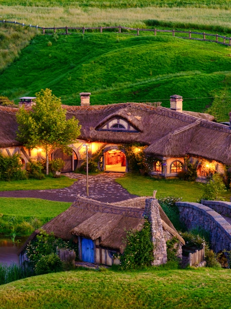 Hobbiton village with thatched cottages and stone bridge, part of Rotorua tour.