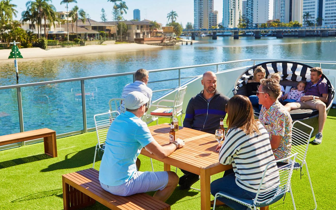 Group enjoying Sea World Afternoon Sightseeing Cruise on deck with city skyline in background.