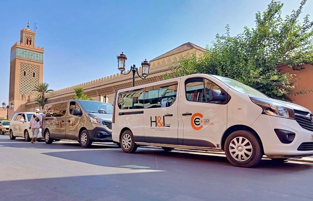 Private transfer vans parked near Marrakesh mosque for Ourika airport service.