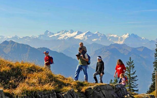 Hikers on a trail with panoramic views of the Swiss Alps during a day trip to Mt. Stanserhorn from Zürich.