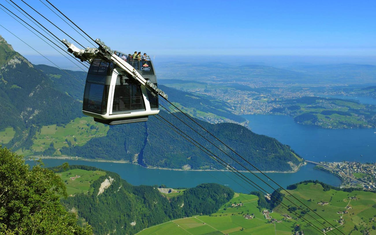 Funicular train ascending Mt. Stanserhorn with views of Lake Lucerne and Swiss Alps.
