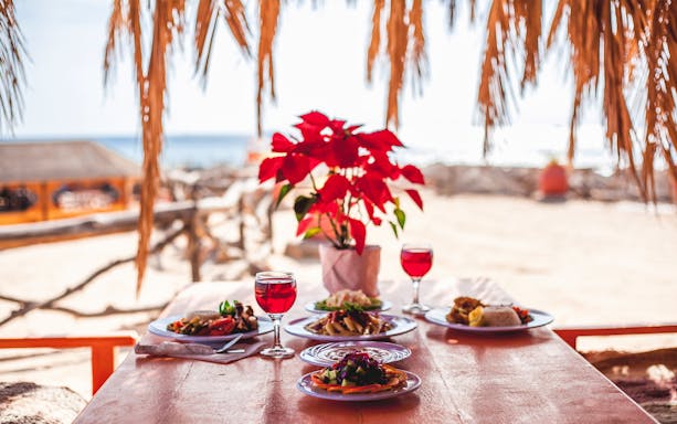 Lunch setup on Giftun Island beach with red flowers and ocean view.