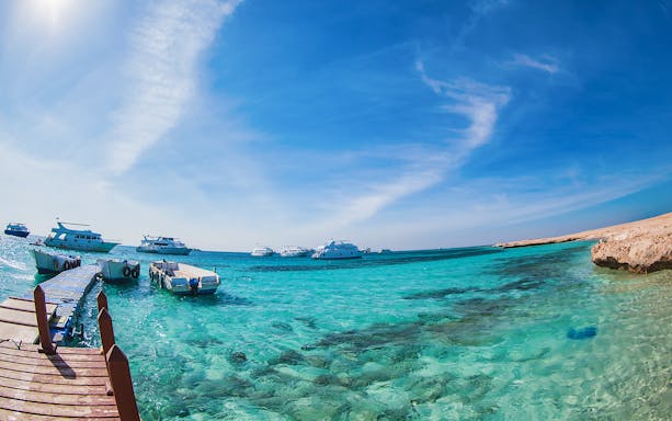 Boats anchored near a pier on clear turquoise waters at Giftun Island, Egypt.