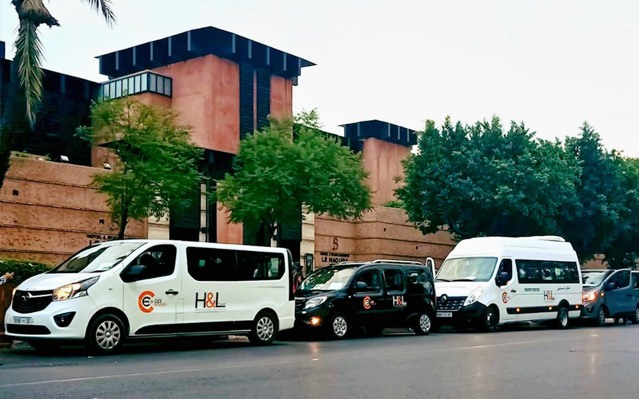 Private transfer vehicles parked outside Marrakesh building for Essaouira Airport service.