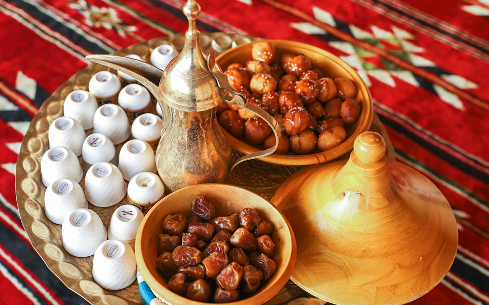 Traditional Arabian coffee and sweets on a tray during a morning camel safari.