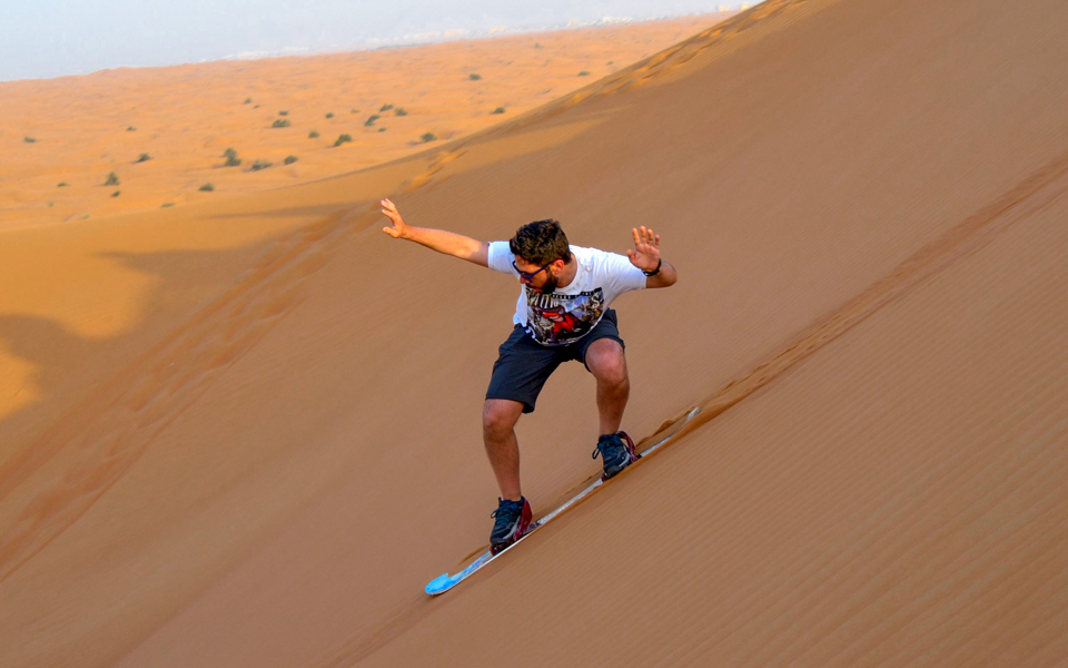 Sandboarding on a desert dune during a morning camel safari.