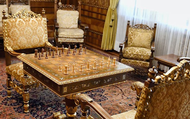Chess set on ornate table in Ceausescu Mansion's opulent room, part of Fast Track Guided Tour.