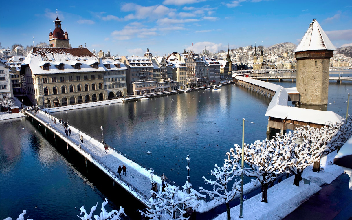 Snow-covered Chapel Bridge and Lucerne cityscape in winter, Switzerland.