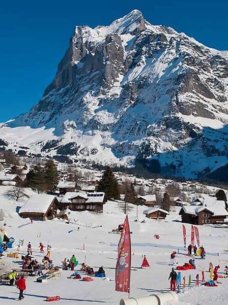 Skiers enjoying slopes in Jungfrau Region, Swiss Alps, with snowy mountain backdrop.