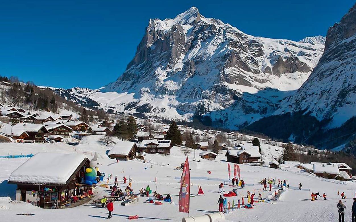 Skiers enjoying slopes in Jungfrau Region, Swiss Alps, with snowy mountain backdrop.
