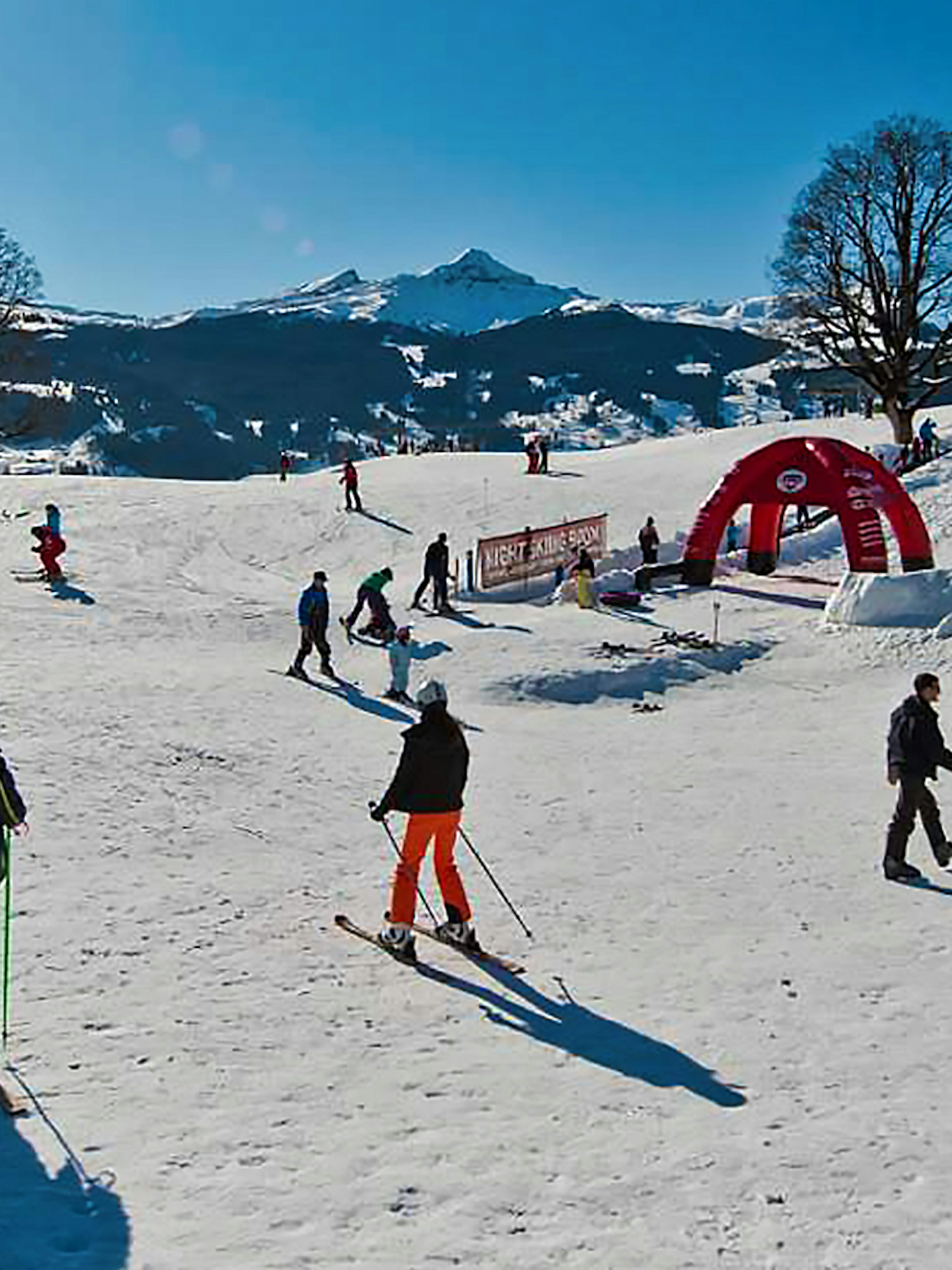 Skiers enjoying slopes in Jungfrau Region, Switzerland, with snowy mountains in the background.