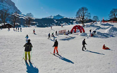 Skiers enjoying slopes in Jungfrau Region, Switzerland, with snowy mountains in the background.