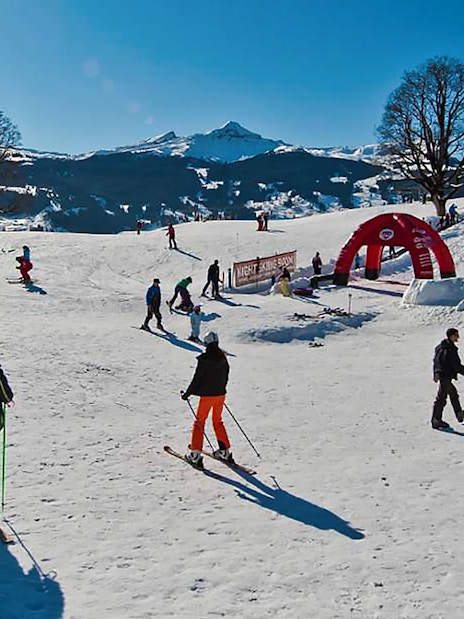Skiers enjoying slopes in Jungfrau Region, Switzerland, with snowy mountains in the background.