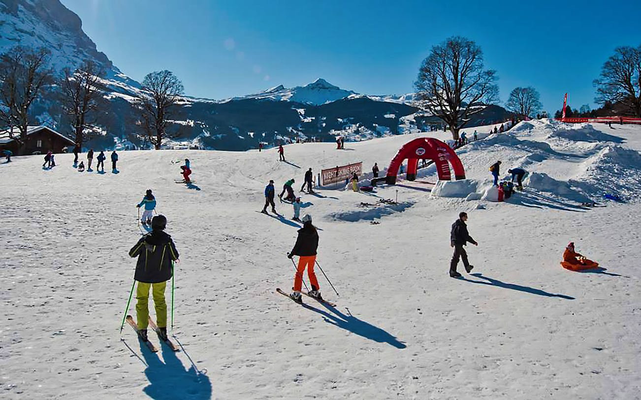 Skiers enjoying slopes in Jungfrau Region, Switzerland, with snowy mountains in the background.
