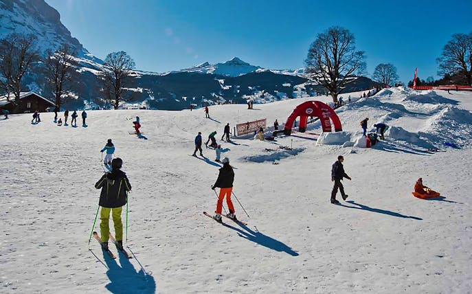 Skiers enjoying slopes in Jungfrau Region, Switzerland, with snowy mountains in the background.