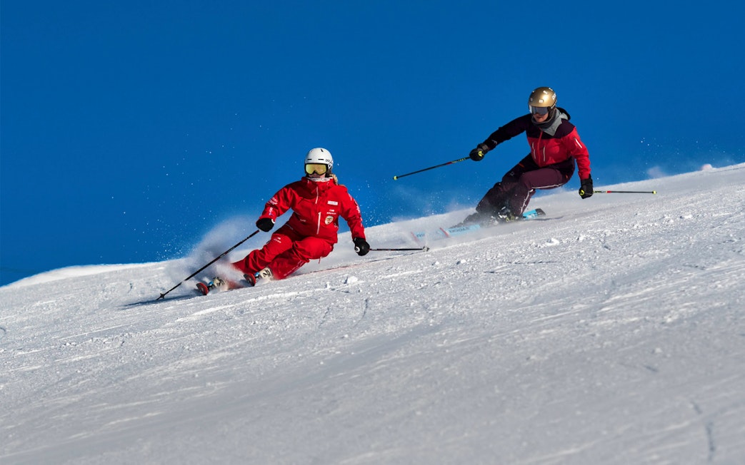 Skiers on a snowy slope in Grindelwald during a beginner ski lesson.