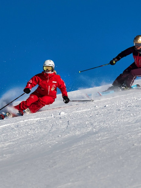Skiers on a snowy slope in Grindelwald during a beginner ski lesson.