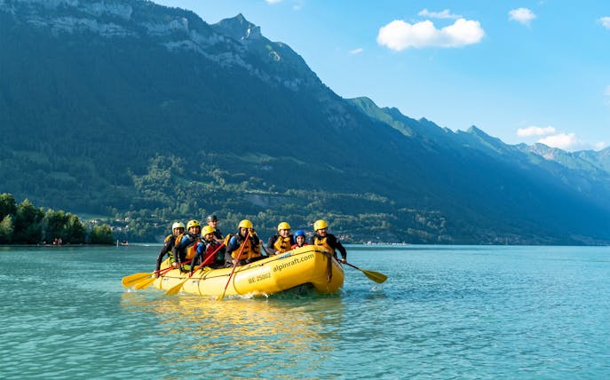 Family rafting on Lake Brienz with mountain backdrop.