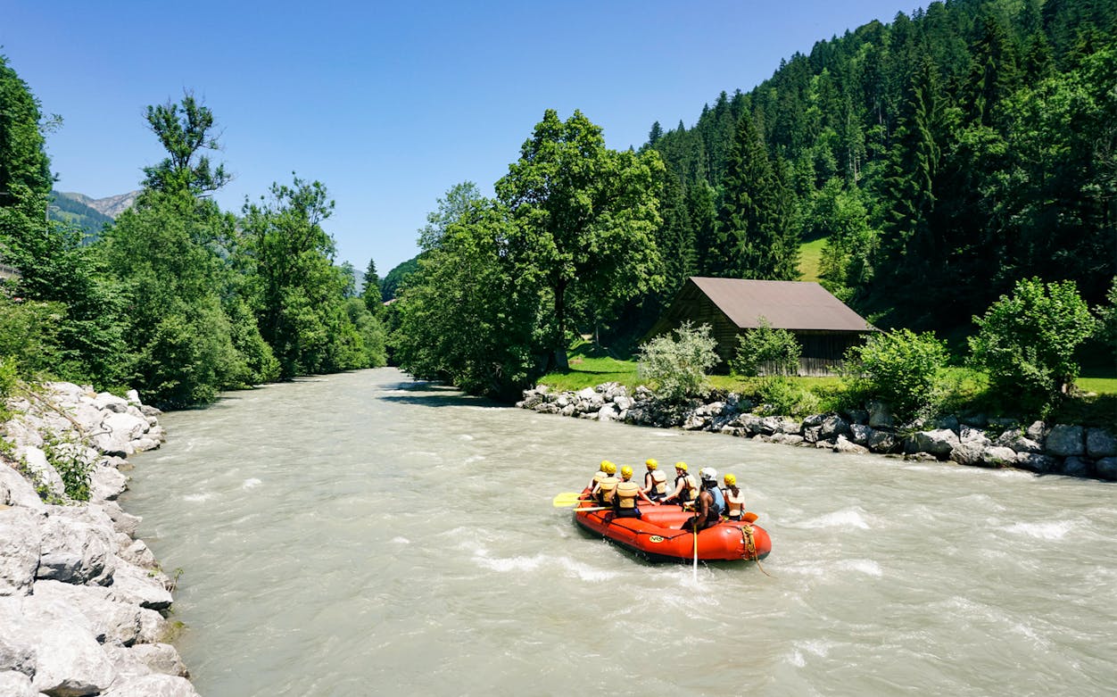 Rafting group on the Aare River near Thun, Switzerland, surrounded by lush greenery.