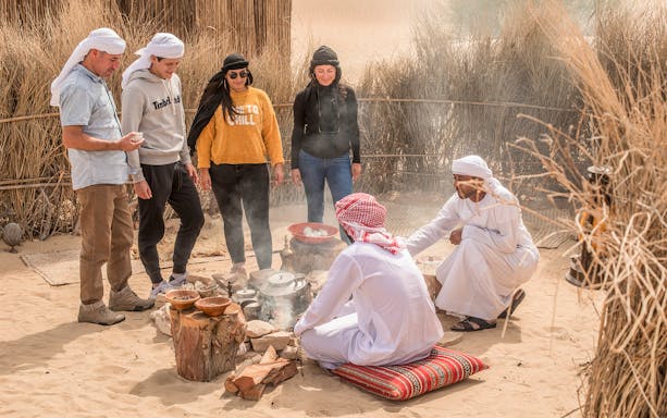 Group enjoying traditional Emirati breakfast around a campfire during a Bedouin culture safari.