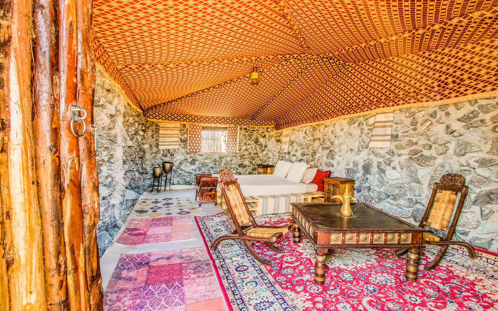Desert safari tent interior with traditional rugs and wooden furniture.