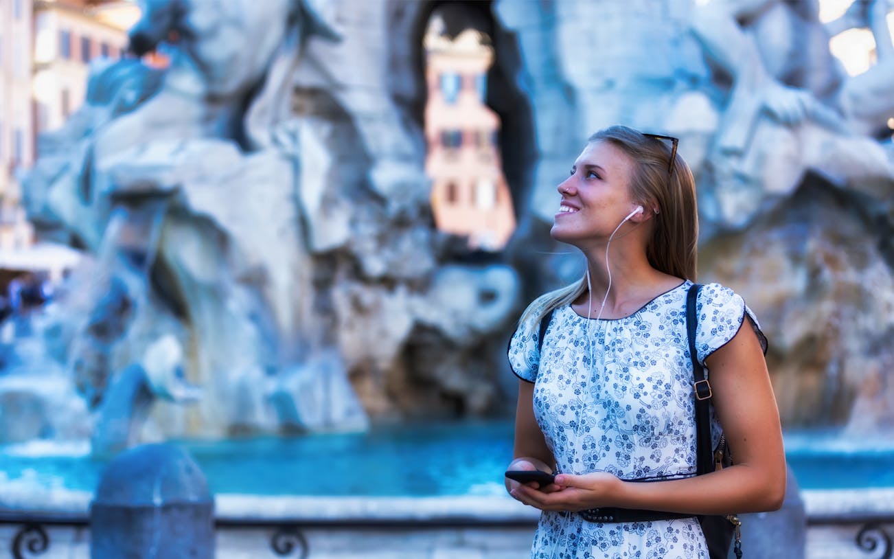 Person enjoying the Trevi Fountain in Rome with headphones, part of the 72-Hour Rome Unlimited Walking Tour Pass.