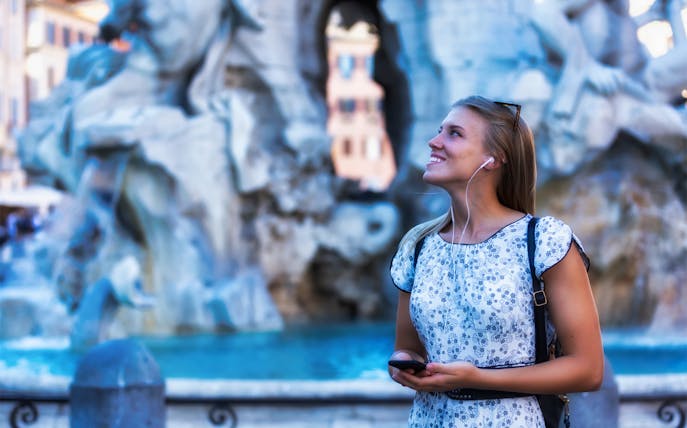 Person enjoying the Trevi Fountain in Rome with headphones, part of the 72-Hour Rome Unlimited Walking Tour Pass.