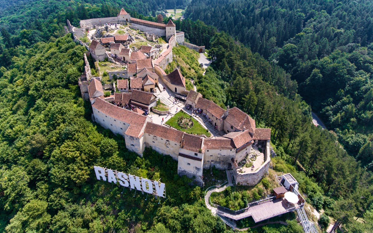 Aerial view of Rasnov Fortress surrounded by forest, part of the Skip the Line Guided Tour.