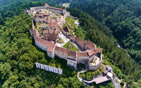 Aerial view of Rasnov Fortress surrounded by forest, part of the Skip the Line Guided Tour.