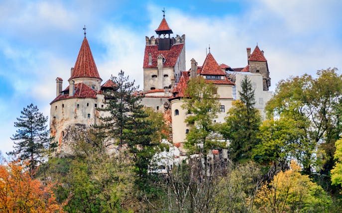 Bran Castle surrounded by autumn trees, part of a guided tour in Romania.