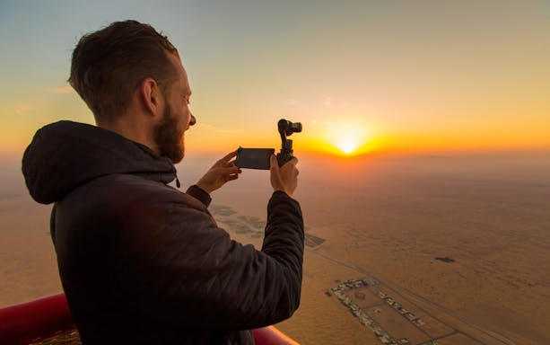 Hot air balloon over Dubai desert landscape during sunrise, Balloon Adventures tour.
