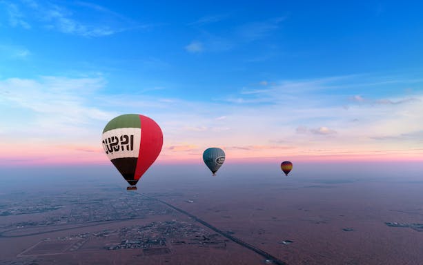 Group of tourists enjoying a sunrise Balloon Adventure - Hot Air Balloon Ride over the serene desert landscape in Dubai