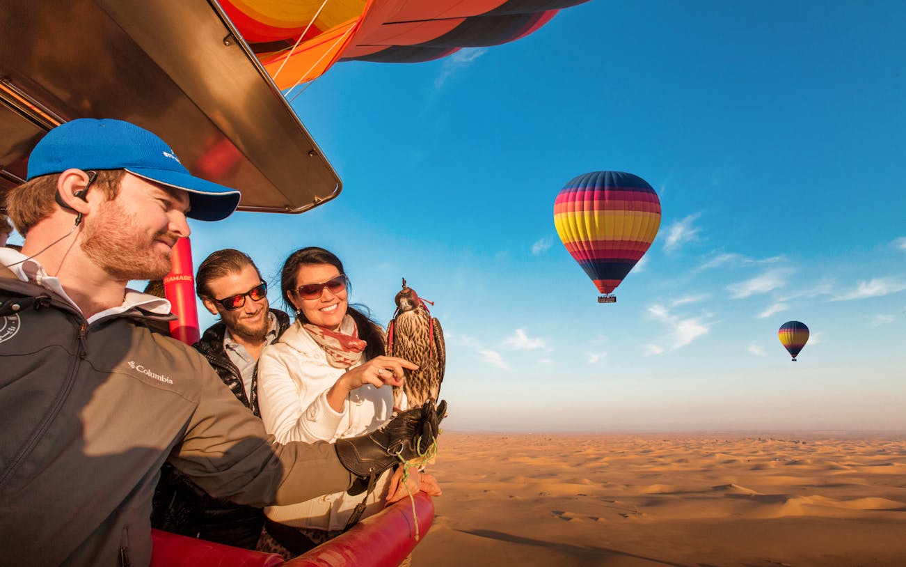 Hot air balloon over Dubai desert landscape during sunrise.