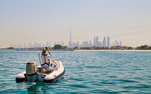 Person on a self-drive boat with Dubai skyline in the background.