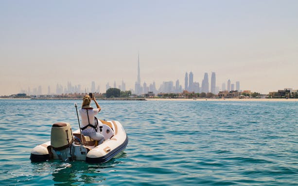 Person on a self-drive boat with Dubai skyline in the background.