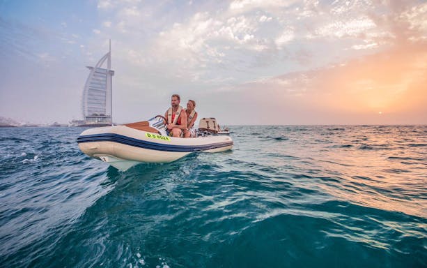 Self-drive boat near Burj Al Arab during sunset in Dubai.