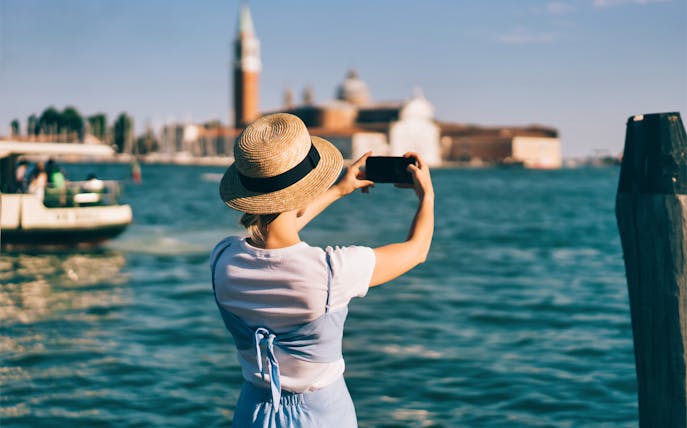 Tourist taking photo of San Giorgio Maggiore from Venice waterfront.